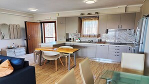 A compact kitchen with a dining area, a refrigerator, and a window with curtains. - Villa Traditional Estate Heated Pool (Nea Propontida)