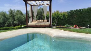 A clear swimming pool with a wooden pergola and a cushioned seating area. - Villa Traditional Estate Heated Pool (Nea Propontida)