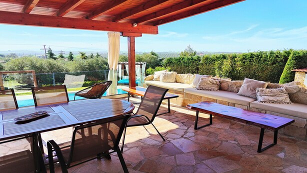 An outdoor patio with a pool, seating area, and stone flooring. - Villa Traditional Estate Heated Pool (Nea Propontida)