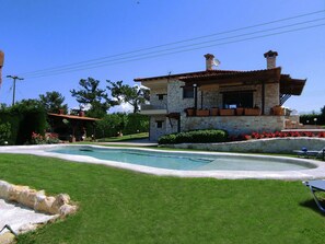 A stone house with a swimming pool, surrounded by well-maintained lawn and potted plants. - Villa Traditional Estate Heated Pool (Nea Propontida)