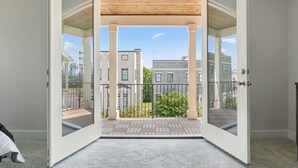 A room with a large sliding glass door leading to an outdoor balcony with a view of neighboring buildings. - ★HOT AREA★ 5min to Broadway • SLEEPS 12 • SPACIOUS  (Nashville)