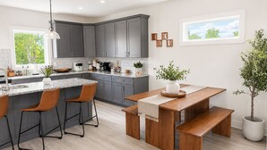 A modern kitchen with grey cabinets, a granite countertop, and a wooden dining set. - ★HOT AREA★ 5min to Broadway • SLEEPS 12 • SPACIOUS  (Nashville)