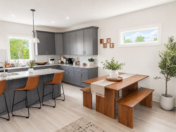 A modern kitchen with grey cabinets, a granite countertop, and a wooden dining set.
