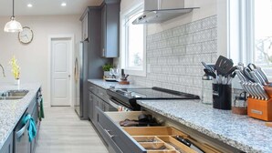 A modern kitchen with grey cabinets, a stainless steel range hood, and a large window providing natural light. - ★HOT AREA★ 5min to Broadway • SLEEPS 12 • SPACIOUS  (Nashville)