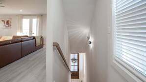 A staircase leading to a second floor with a wooden handrail, white walls, and a window with blinds. - ★HOT AREA★ 5min to Broadway • SLEEPS 12 • SPACIOUS  (Nashville)