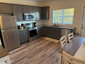 Enjoy meal preparation and dining in this kitchen with a refrigerator, microwave, oven, and dining area.