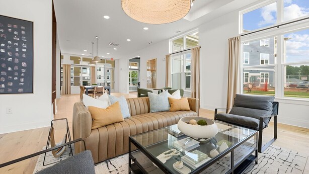 A spacious living room with a leather sofa, a glass coffee table, and a view of the outside. - Modern Comfort Near Mooresville's Attractions (Mooresville)