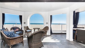 A covered patio with wicker furniture, a table, and a view of the beach. - Luxury Oceanfront Condo - Perfect for Large Families - Steps to the Sand! (Newport Beach)