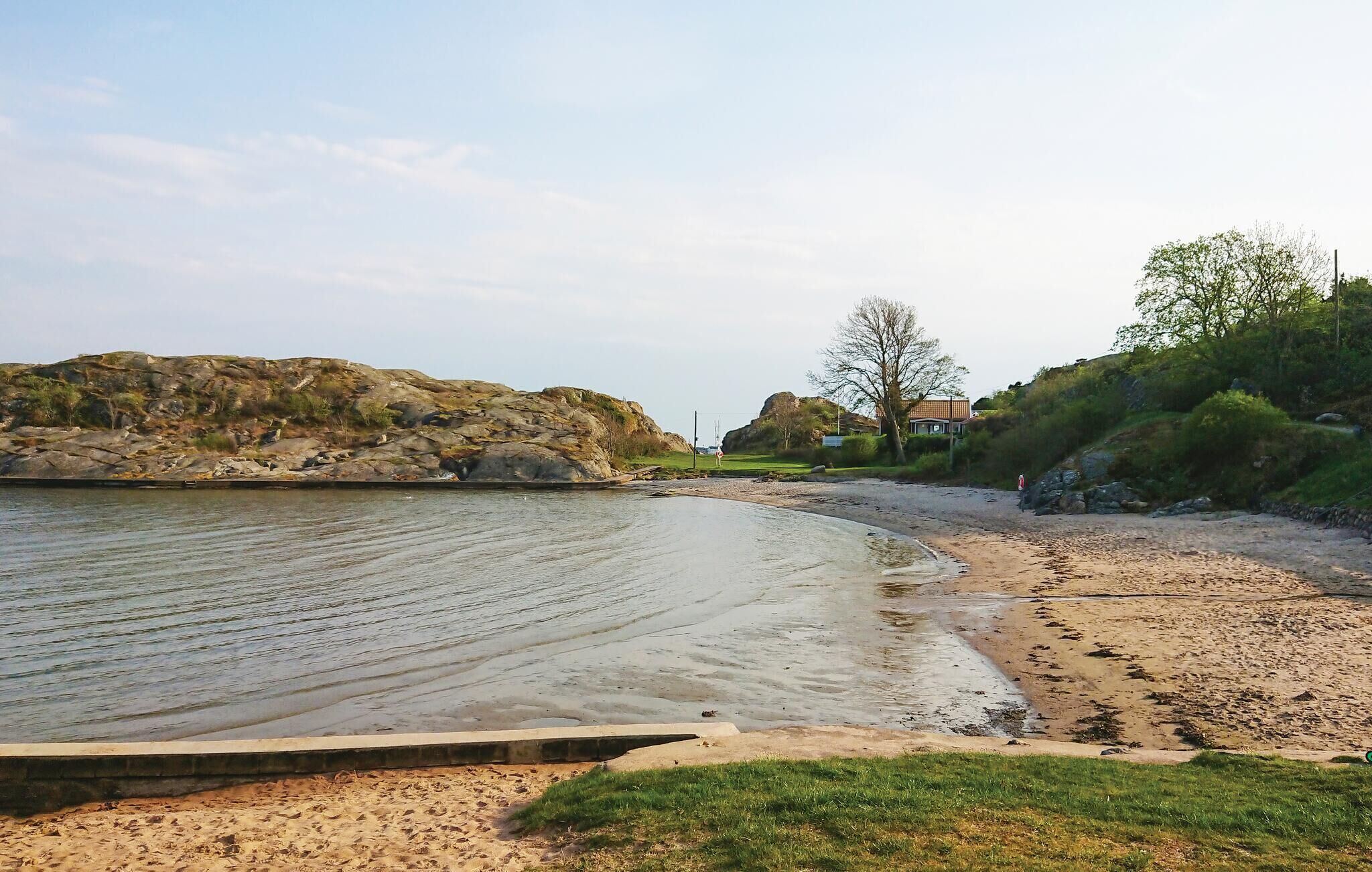 Een strand met een rotsachtige kustlijn, een zandgebied en een gebouw op de achtergrond.