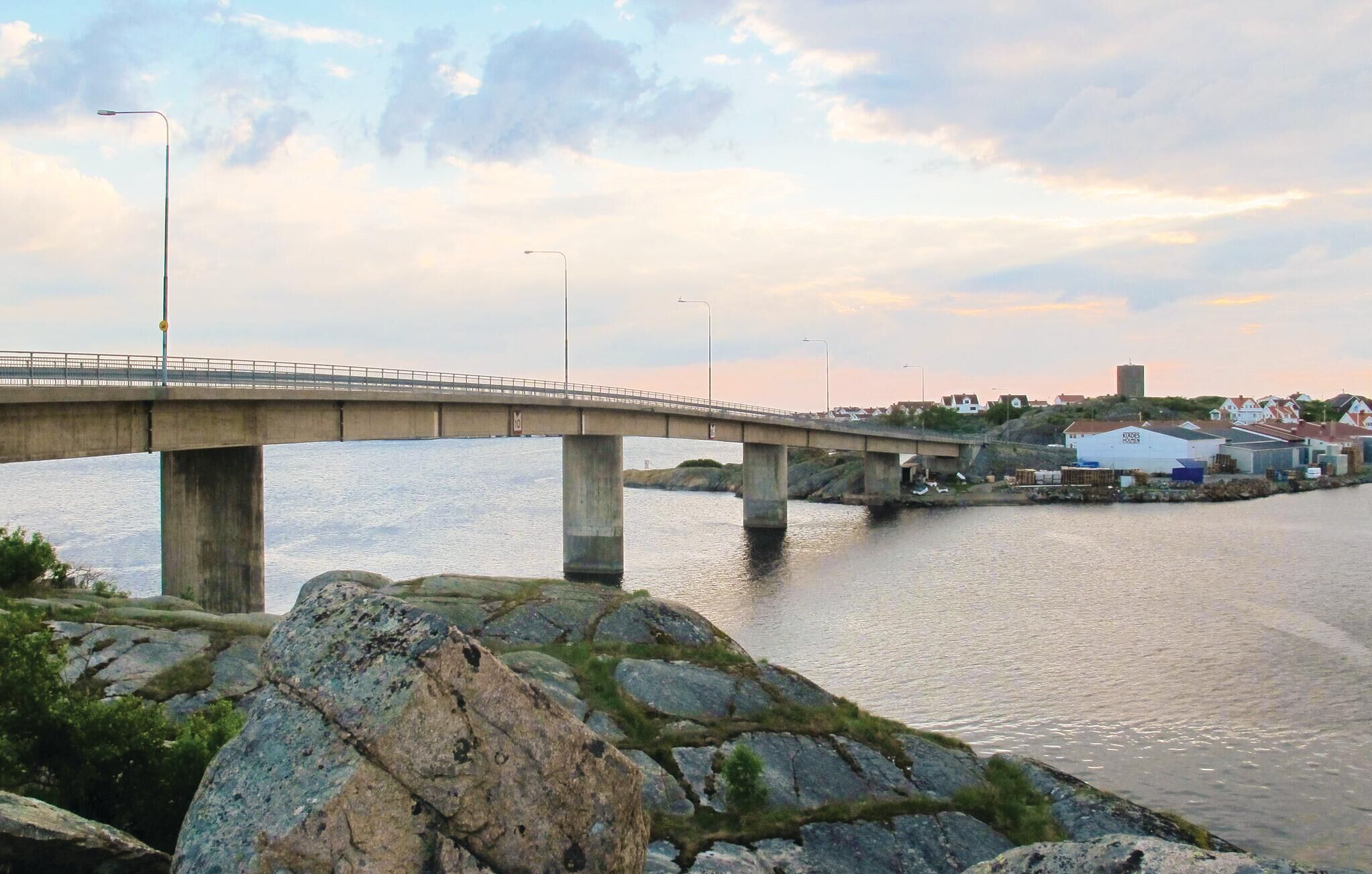 A bridge over a river with houses and a building in the background.