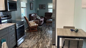 A kitchen with a microwave, oven, and refrigerator, a dining area with a table and chairs, and a living area with a sofa and chairs. - Beautiful 3 bedroom house in Villas NJ- dishwasher, washer/dryer, and ac. (Lower Township)