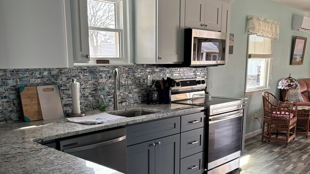 A modern kitchen with grey cabinets, a stainless steel sink, and a built-in oven. - Beautiful 3 bedroom house in Villas NJ- dishwasher, washer/dryer, and ac. (Lower Township)