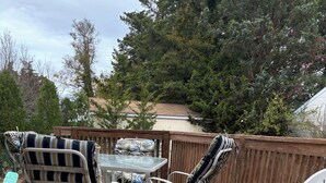 A wooden deck with a table and chairs, surrounded by a wooden fence and trees. - Beautiful 3 bedroom house in Villas NJ- dishwasher, washer/dryer, and ac. (Lower Township)