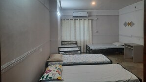 A small, compact room with two single beds, a desk, and a chair.