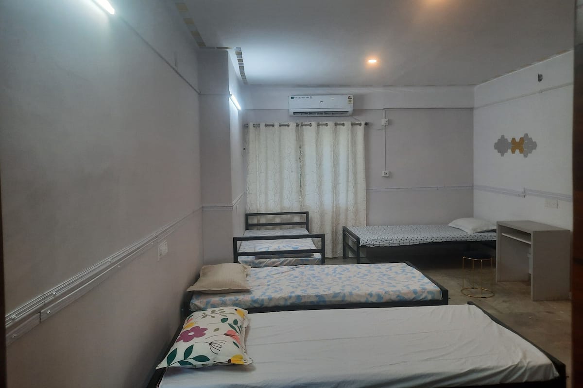 A small, compact room with two single beds, a desk, and a chair.