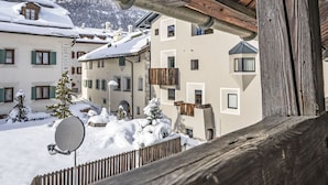 Ein verschneiter Innenhof mit Gebäuden, einem Holzzaun und einer Satellitenschüssel.