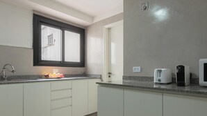 A kitchen with white cabinets, a granite countertop, a window with a black frame, a toaster, and a coffee maker. - MOT Charcas 3000 (Buenos Aires)