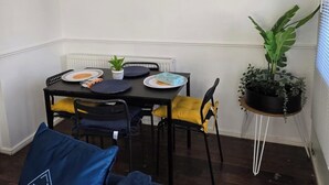 A dining area with a table, chairs, a potted plant, and a framed picture on the wall. - West Winds Sleeps 4 with Garden (Wolverhampton)