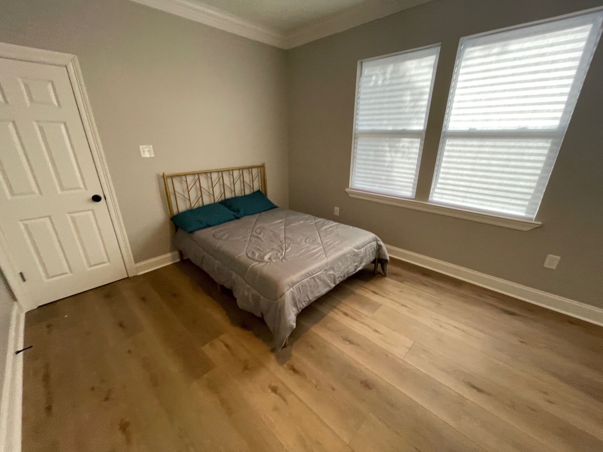 A bedroom with a bed, a door, and two windows.