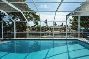 Piscina con cerramiento de vidrio, rodeada de árboles y vistas a una zona residencial.