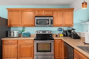 A kitchen with wooden cabinets, a microwave, a toaster, a stove, and a sink.