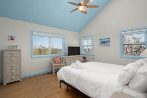 A bedroom with a bed, a desk, a chair, a dresser, and two windows with views. - Duck Blind | Infinity Pool, Sound Views & Sauna (Duck)