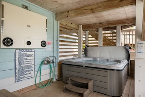 A spa area with a hot tub, wooden deck, and a pool rules sign.