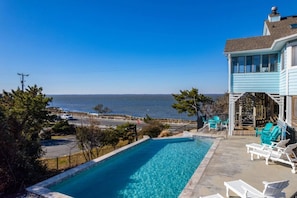 A residential property with a swimming pool, outdoor seating, and a view of the ocean.