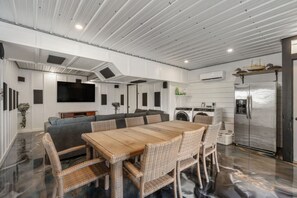 A modern living room with a large sofa, a dining table, and a flat-screen TV.