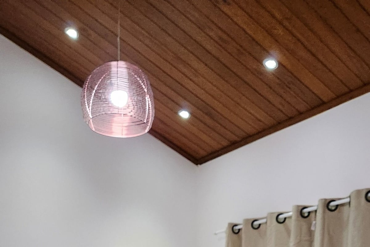 A bedroom with a bed, wooden wardrobe, and a hanging light fixture.