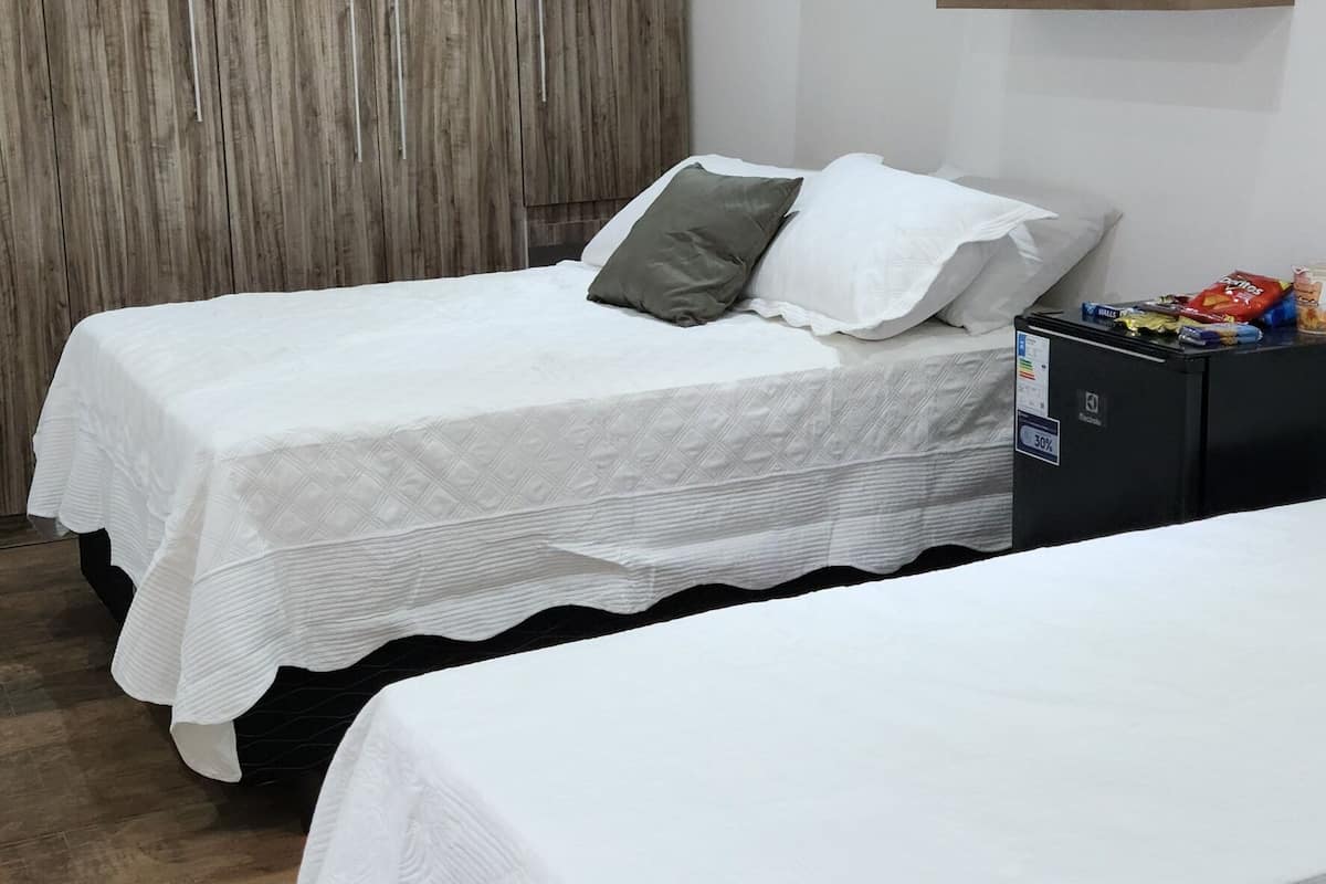 A bedroom with two beds, wooden ceiling, and built-in wardrobe.