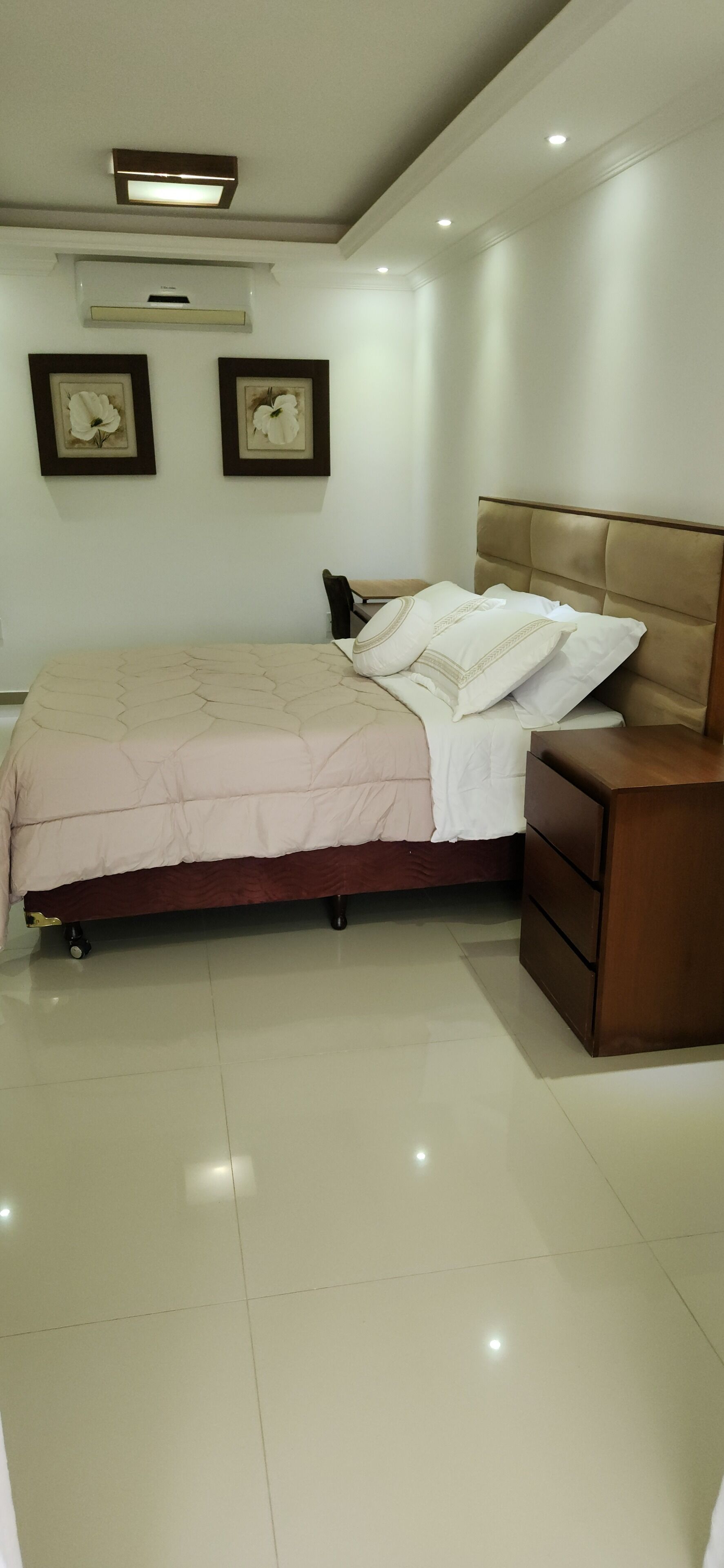 Une chambre à coucher comprenant un lit, une table de chevet et un climatiseur fixé au mur.