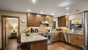A modern kitchen with wooden cabinets, granite countertops, stainless steel appliances, and a large island. - Walk to Uptown + Hot Tub, Firepit, Epic Views (Sedona)