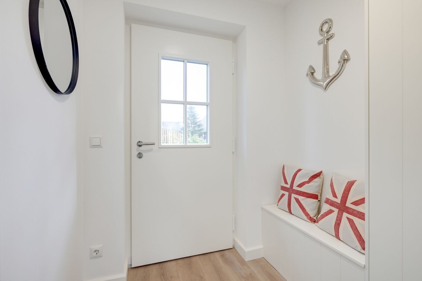 A white door with a small window, a wall-mounted light fixture, and a decorative anchor.