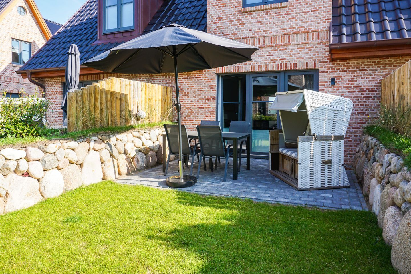 A patio with a table and chairs, a wooden fence, and a stone wall.
