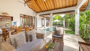 A spacious living area with a pool, wooden furniture, and a thatched roof. - Villa Hijau, Penestanan, Ubud (Ubud, Gianyar Regency)