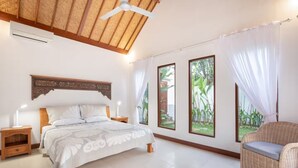 A bedroom with a bed, bedside tables, a chair, and large windows with curtains. - Villa Hijau, Penestanan, Ubud (Ubud, Gianyar Regency)