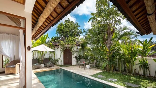 A pool area with a clear view of the pool, surrounded by lush greenery and a covered seating area with chairs and a table. - Villa Hijau, Penestanan, Ubud (Ubud, Gianyar Regency)