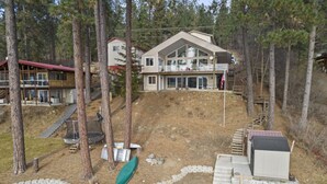 A two-story house with a large deck and a small boat in the yard.