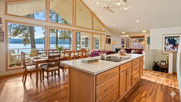 A spacious kitchen with a large island, wooden cabinets, and a view of a lake.