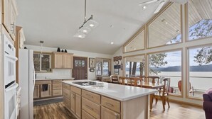 A modern kitchen with wooden cabinets, a large island, and a view of a lake.