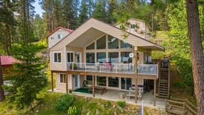 A two-story house with a balcony, a deck, and a small outdoor seating area.