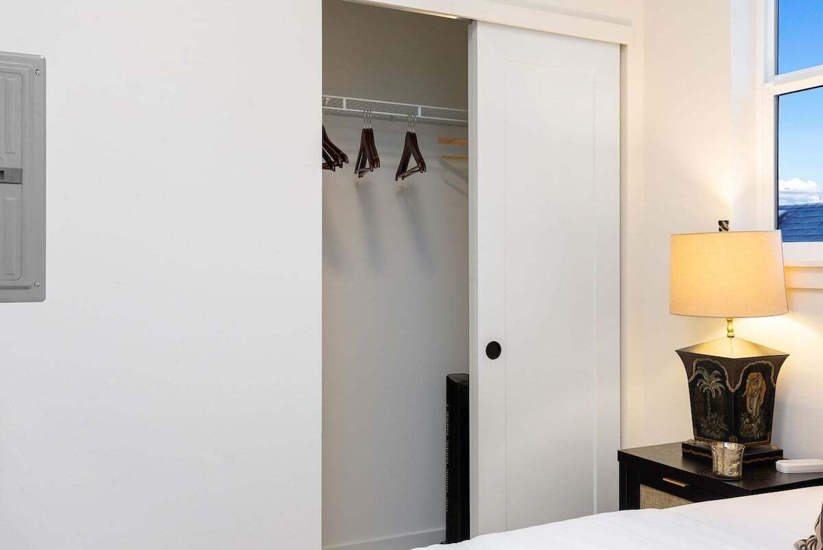 Une chambre d’hôtel avec un lit, une table de chevet avec une lampe, une armoire et une fenêtre donnant sur un beau paysage.