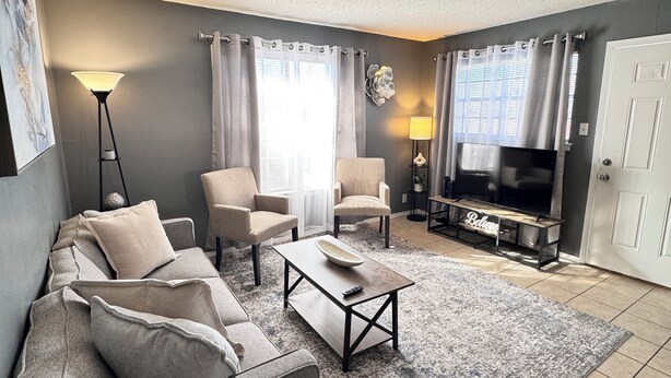 Un salon avec un canapé gris, une table basse et un meuble pour la télévision, sur lequel est posée une télévision à écran plat.