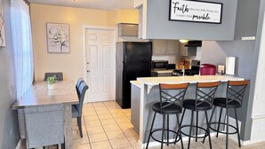 Une cuisine moderne dotée d’un îlot central, de tabourets de bar et d’une table à manger avec des chaises.