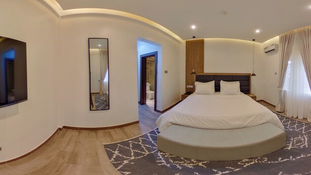 Een moderne hotelkamer met een groot bed, een spiegel, een nachtkastje en uitzicht op de gang.