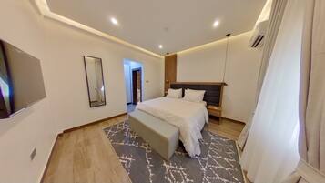 Une chambre d’hôtel moderne dotée d’un grand lit, de tables de chevet, d’un téléviseur à écran plat et d’un miroir.