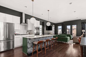 A modern kitchen with white cabinets, stainless steel appliances, and a green accent wall.