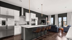 A modern kitchen with a central island, stainless steel appliances, and a bar area. - Arch One ~ Joint Listing ~ Two Units ~ 24 Beds in Gulch ~ Free Parking ~ Eight Clean Private Suites (Nashville)