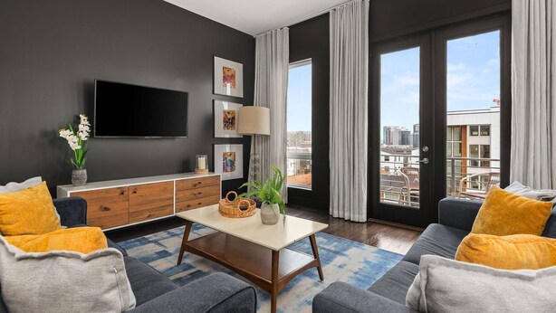 A modern living room with a flat-screen TV, artwork, a coffee table, and a sofa with cushions. - Arch One ~ Joint Listing ~ Two Units ~ 24 Beds in Gulch ~ Free Parking ~ Eight Clean Private Suites (Nashville)